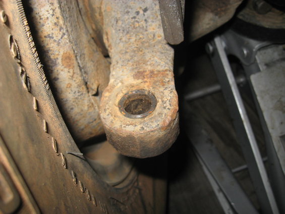 Close-up of a rusty suspension part with a hole in it
