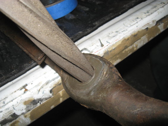 Close-up of a metal tool with a blue tape roll in the background