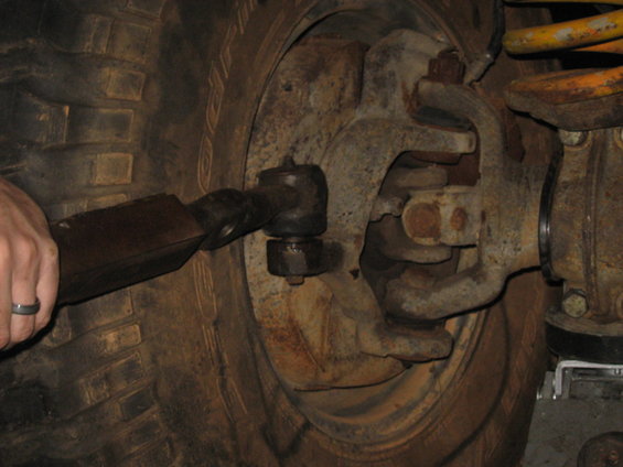 Close-up of a vehicle's steering linkage and suspension components near the wheel hub