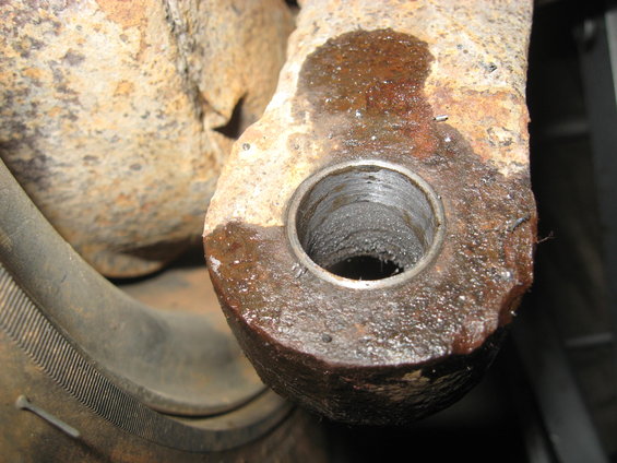 Close-up of a rusted metal part with a threaded hole and oil residue