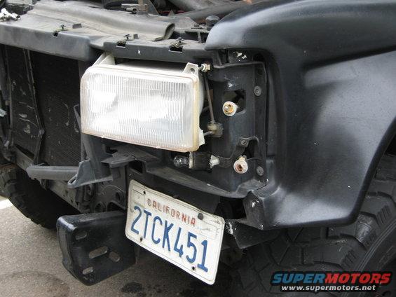 Black truck front end with missing headlight assembly and damaged bumper. California license plate 2TCK451 is visible
