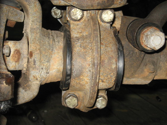 Close-up of a rusty driveshaft U-joint with rubber boots and bolts