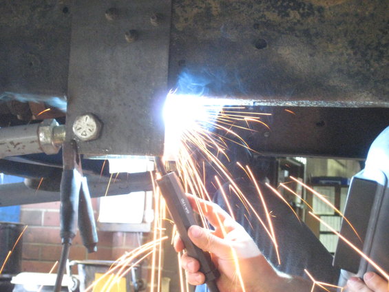 Welding sparks fly from a metal frame repair on a vehicle chassis