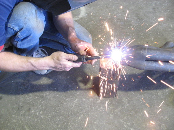 Man welding an exhaust pipe with sparks flying