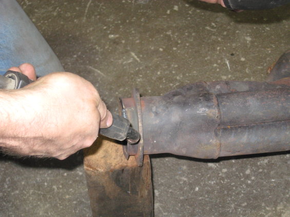 hand holding tool to work on exhaust pipe joint