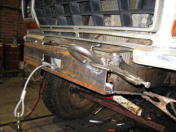 Custom steel bumper being welded onto a 1978 Ford Bronco front end. A tow cable is attached