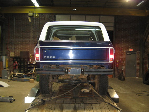 Blue 1978 Ford Bronco on a trailer, rear view. White hardtop, "FORD" tailgate badge