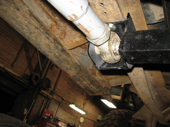 Undercarriage of a vehicle with rusty frame rails, a driveshaft, and a u-joint