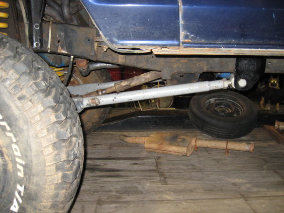 Close-up of vehicle undercarriage showing suspension, exhaust, and a spare tire. BFGoodrich lettering visible on the main tire