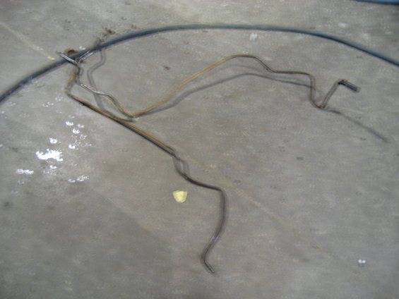 Bent metal brake lines lying on a concrete floor