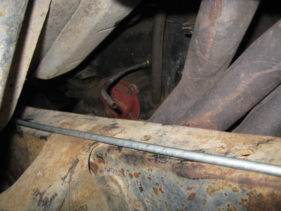 Red fuel filter and exhaust manifold under a vehicle