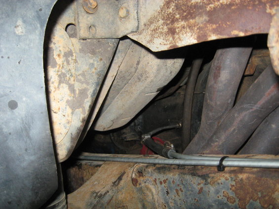 close-up of rusty frame, exhaust pipes, and fuel lines under a vehicle