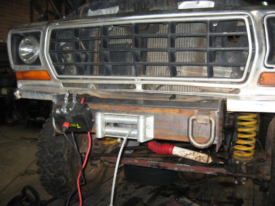 1978 Ford Bronco front end with a winch mounted on a custom bumper. Yellow coil spring visible