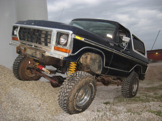 Dark blue 1978 Ford Bronco on gravel, lifted with large tires