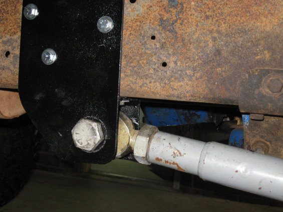 Close-up of a vehicle's suspension linkage with bolts and rusty frame