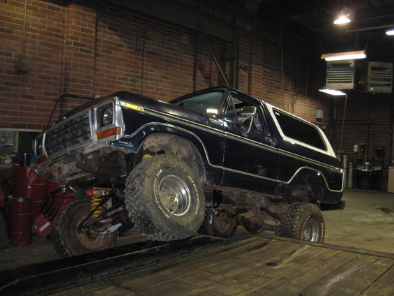 Dark blue 1978 Ford Bronco with white top on a lift, 3q-front view