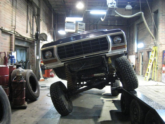 1978 Ford Bronco front view, lifted and on a trailer in a garage