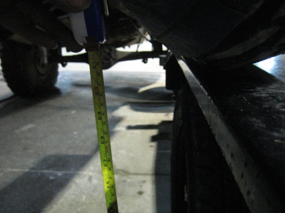 Undercarriage of a vehicle with a yellow measuring tape showing approximately 27 inches