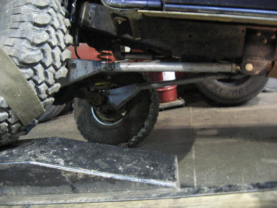 Close-up of a vehicle's suspension and large tire, possibly an off-road vehicle, on a ramp