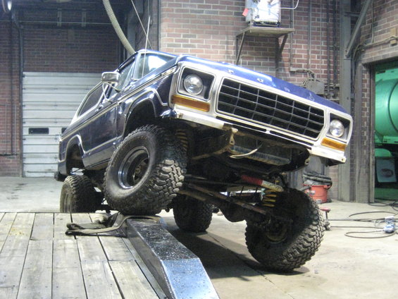 Blue 1978 Ford Bronco on a lift, front 3/4 view, showing lifted suspension and off-road tires