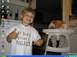 1986 Ford Bronco - A young boy proudly displays his t-shirt while a baby sits in a high chair behind him.