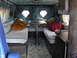 1978 Ford E150 - The interior of a camper van features two benches, a table, and diamond-shaped windows.