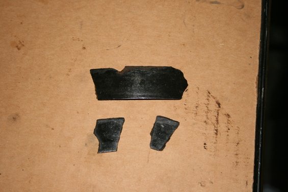 Broken black transmission parts on a brown surface