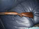 1991 Ford Bronco - A rifle with a wooden stock is shown resting on a dark blue leather surface.