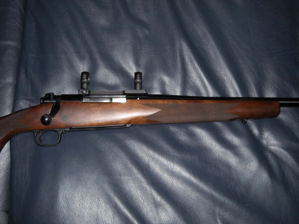 Side view of a wooden rifle with black scope mounts