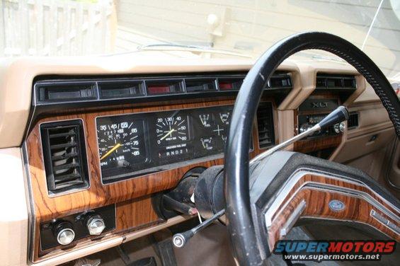 Tan dashboard with wood grain trim, showing a speedometer, fuel gauge, and XLT badging