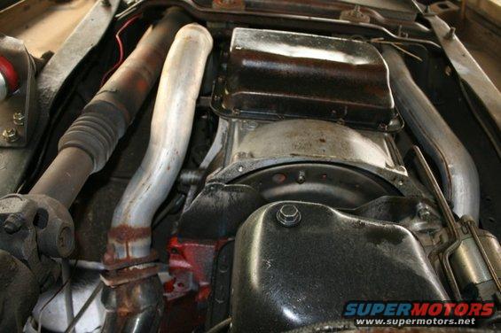 Underside view of engine oil pan and exhaust pipes with rust
