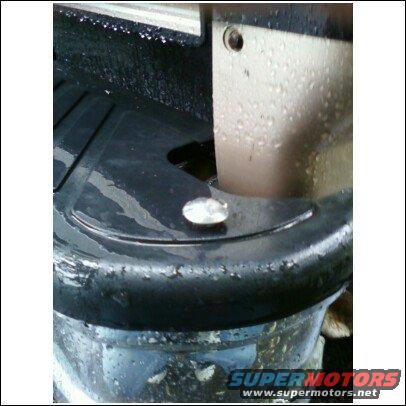 Close-up of a wet wheel well with a black plastic liner and a silver lug nut