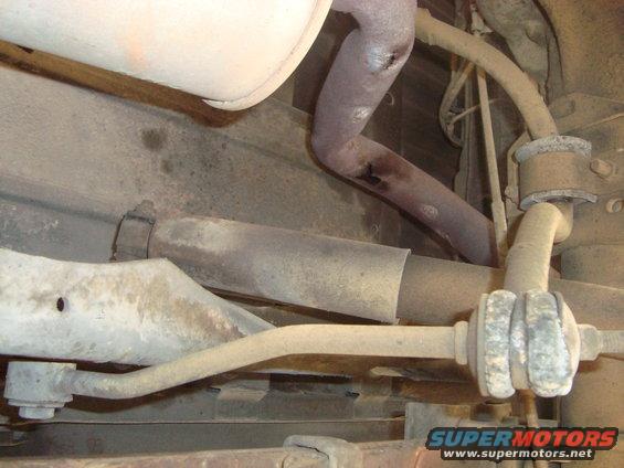 Underside of a vehicle showing rusty exhaust pipes and suspension parts
