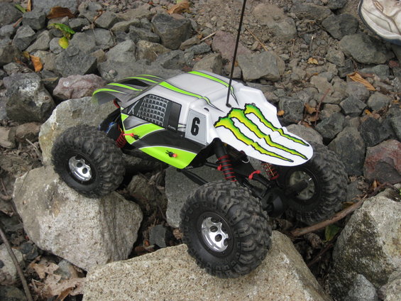 Remote control rock crawler with Monster Energy graphics on a rocky surface