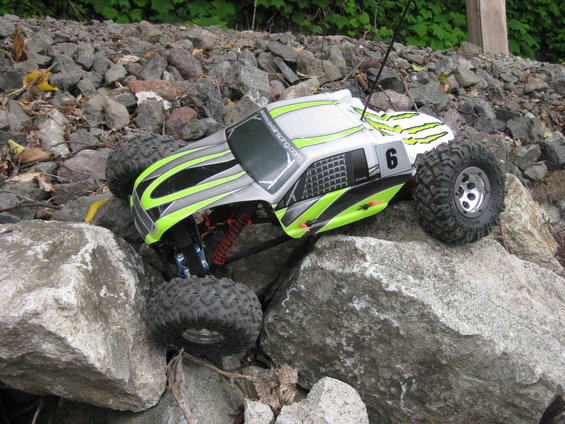 RC rock crawler with green and black graphics on rocks. Number 6 on side