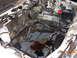 1995 Ford Taurus - The engine bay shows signs of fluid leaks, with brake fluid and oil spilled on the floor.