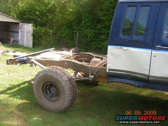 Truck cab and frame with one large tire visible. The body is two-tone blue and white