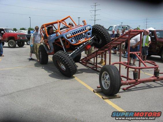 Custom Jeep on a ramp with large tires, people watching