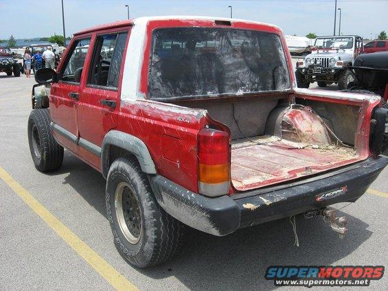Red Jeep Cherokee sport utility vehicle modified into a pickup truck, rear view