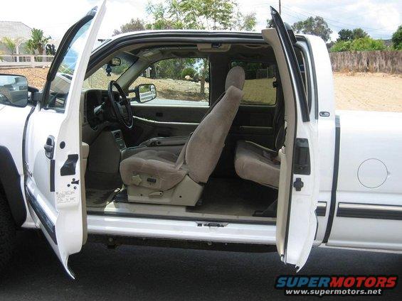 Interior view of a white pickup truck with front and rear doors open, showing cloth seats and dashboard