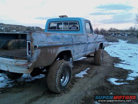 Blue Ford F-Series truck with mud-caked tires and body, seen from the rear