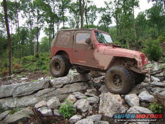 Red 2003 Jeep Wrangler navigating rocky terrain