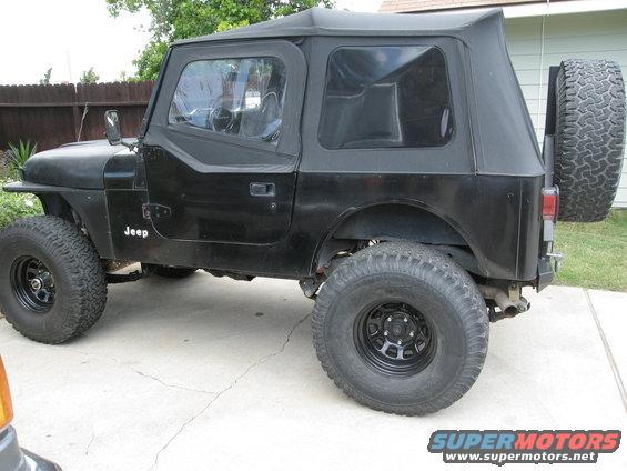 Black Jeep CJ with soft top and spare tire on back. Has 'Jeep' text on fender