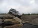 1991 Ford Bronco - Hummer H3 navigating a rocky off-road course under an overcast sky.
