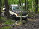 1991 Ford Bronco - 1991 Ford Bronco navigating a rocky trail through a dense forest with another vehicle following.