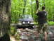 1991 Ford Bronco - A Ford Bronco navigates a challenging rocky path through a dense forest.