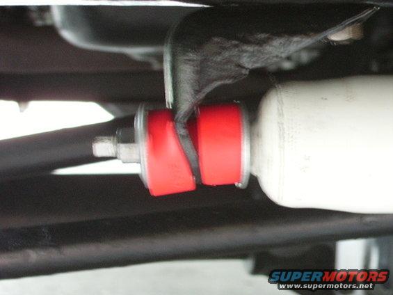 Close-up of red suspension bushings and a white shock absorber on a vehicle's undercarriage