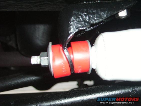 Close-up of red suspension bushings on a white shock absorber, with black metal components visible