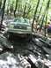1991 Ford Bronco - A Ford Bronco is driven over large rocks on a wooded trail.