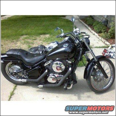 Black motorcycle parked on a concrete path, side view. Chrome accents on engine and exhaust pipes